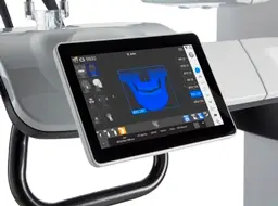 Cyfrowy tablet wyświetla skan dentystyczny 3D w kolorze niebieskim, podkreślając tomografię zatok, zamontowaną na nowoczesnym stanowisku dentystycznym z różnymi elementami sterującymi i sprzętem widocznymi w tle.